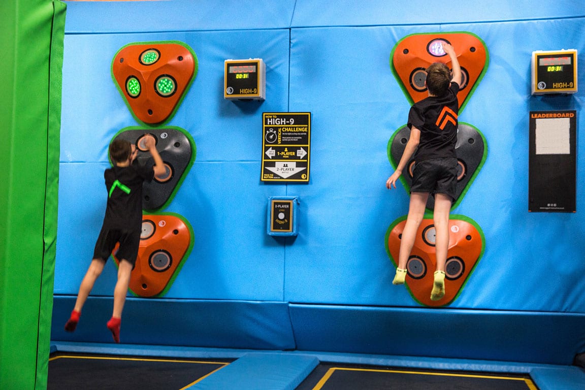 Two children bouncing on trampolines attempting to press various buttons.