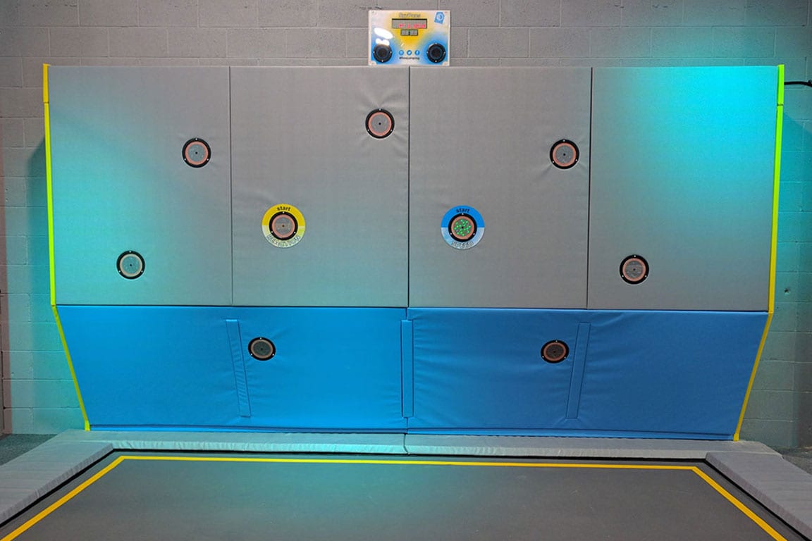 A wall with various buttons to press above a trampoline.