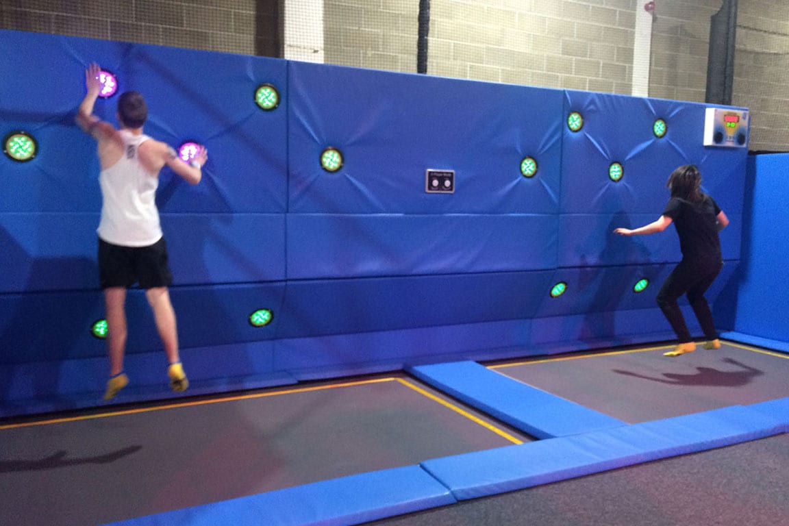 Two park goers bounce on trampolines.