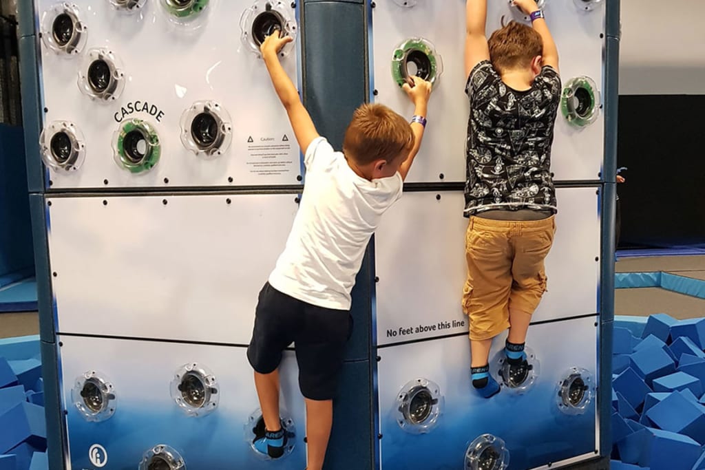 Two children climbing a Rugged Interactive climbing wall.
