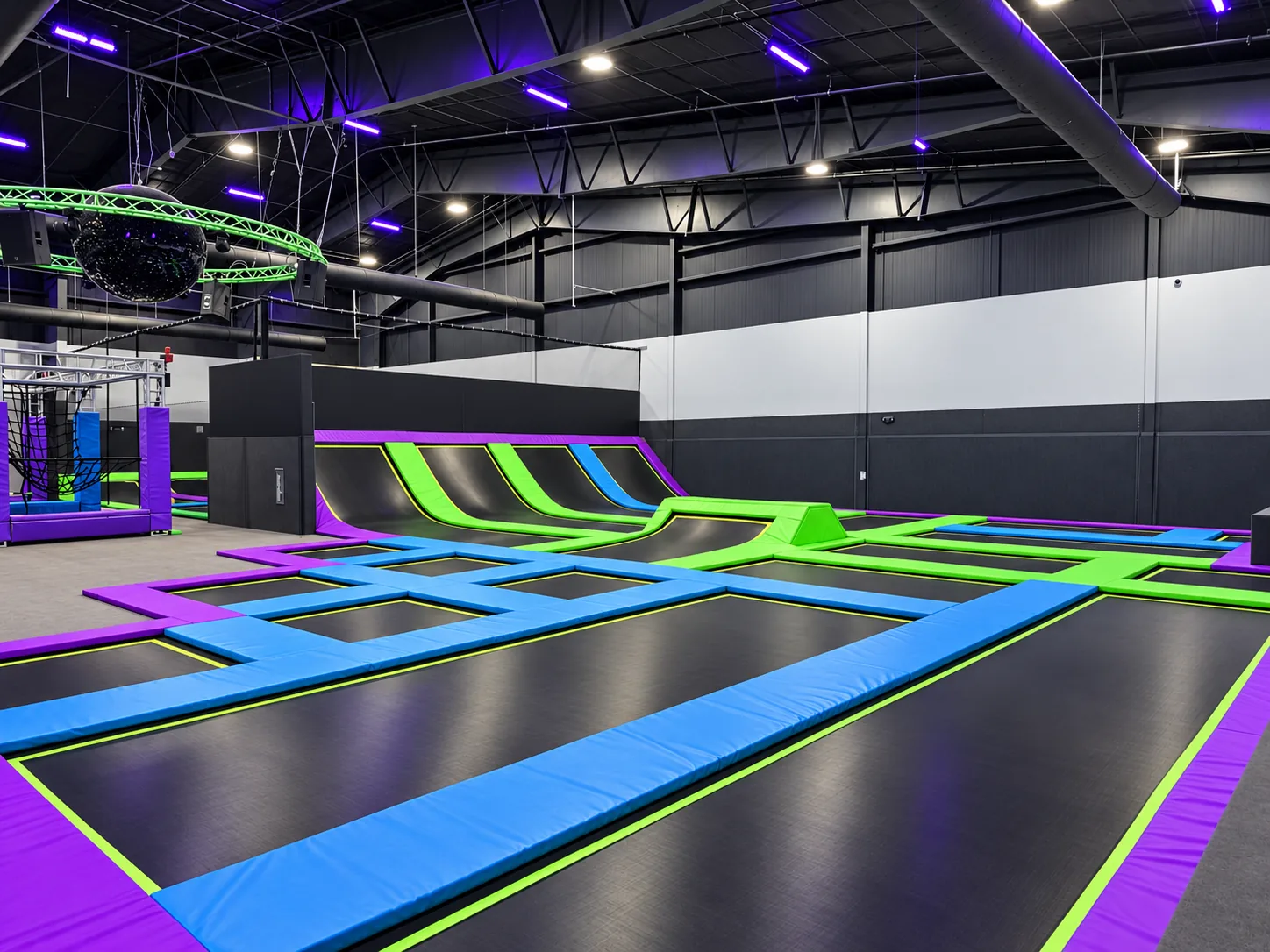 Freestyle trampoline court with blue and green pads and angled wall ramps