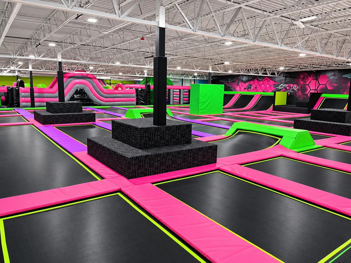 Freestyle trampoline court with padded column platforms and green balance beams