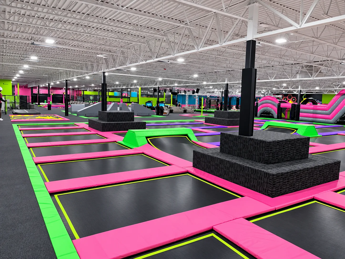 Wide view of a freestyle trampoline court with pink and green pads